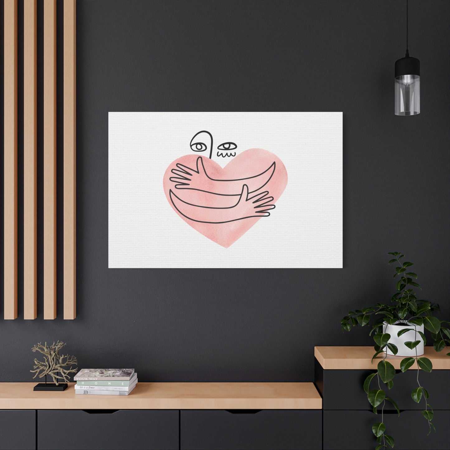 Framed artwork of hands holding a heart on a dark wall with minimal decor.