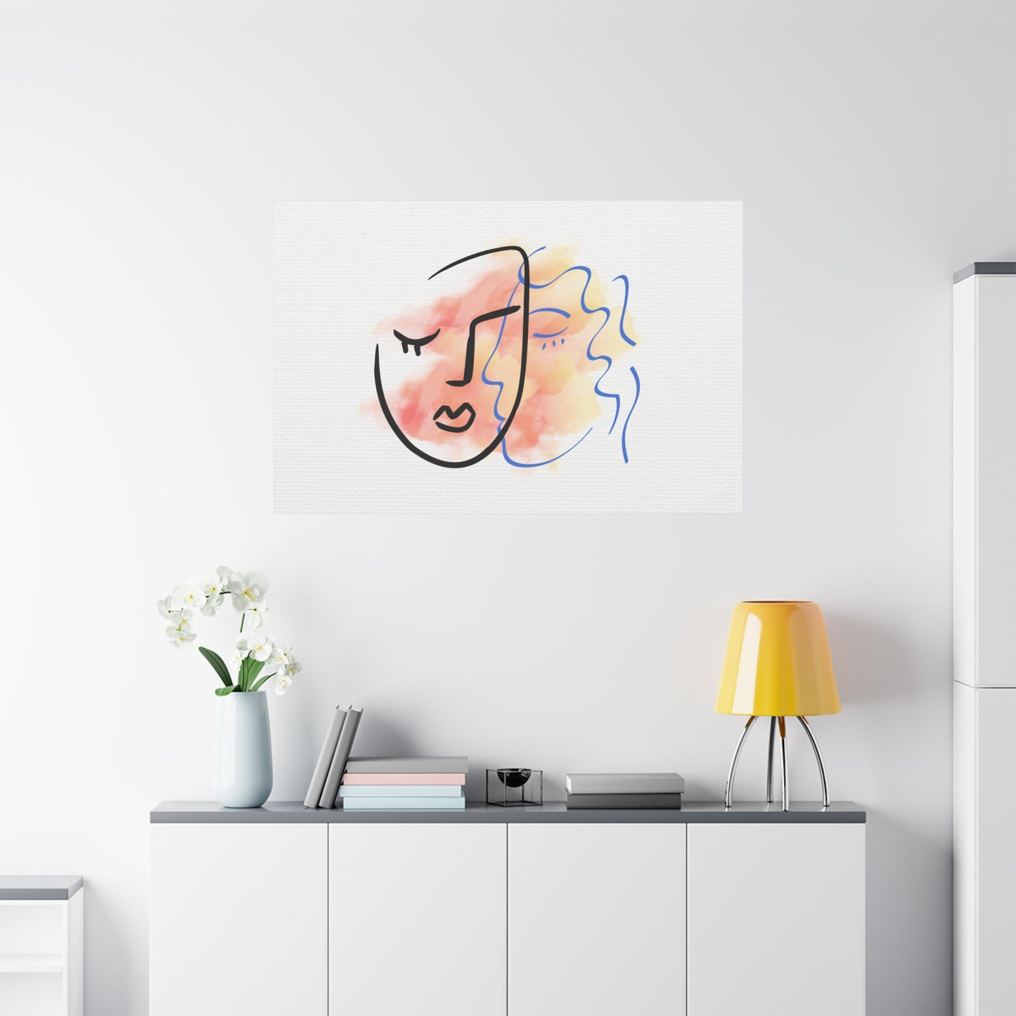 Abstract art piece on a wall above a white cabinet with a yellow lamp and plant.