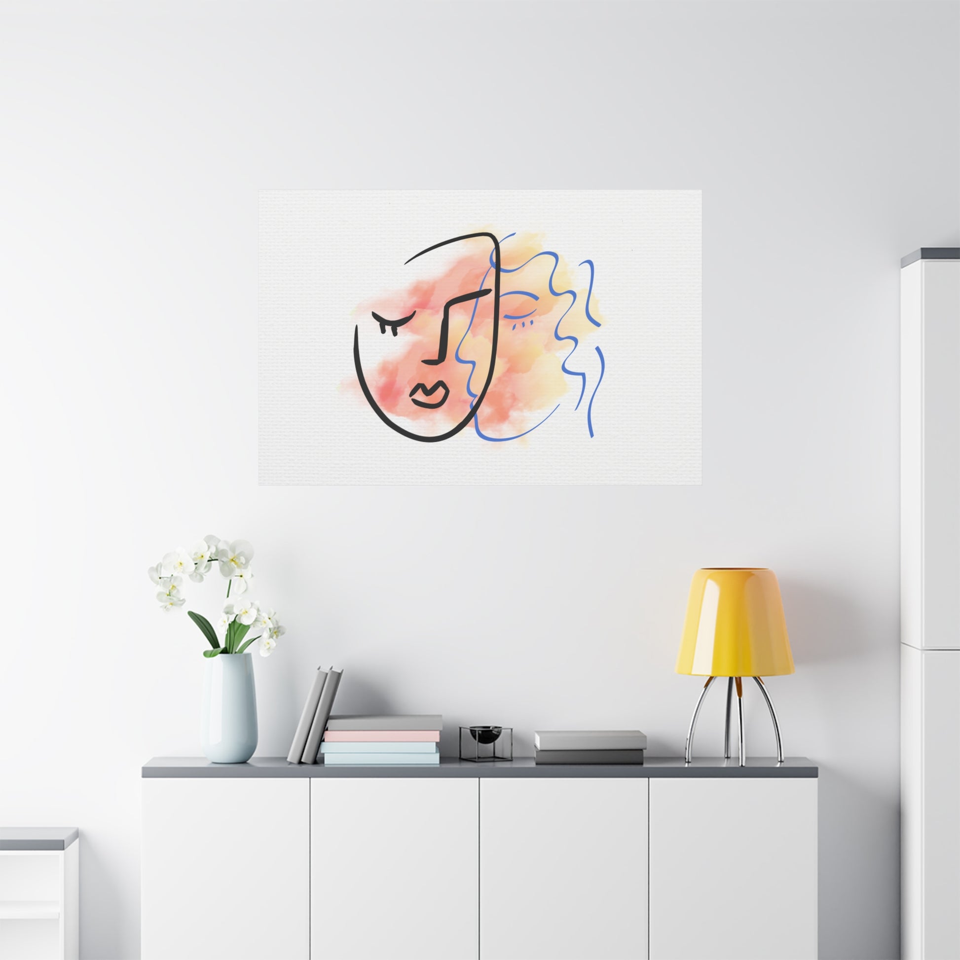 Abstract art piece on a wall above a white cabinet with a yellow lamp and plant.