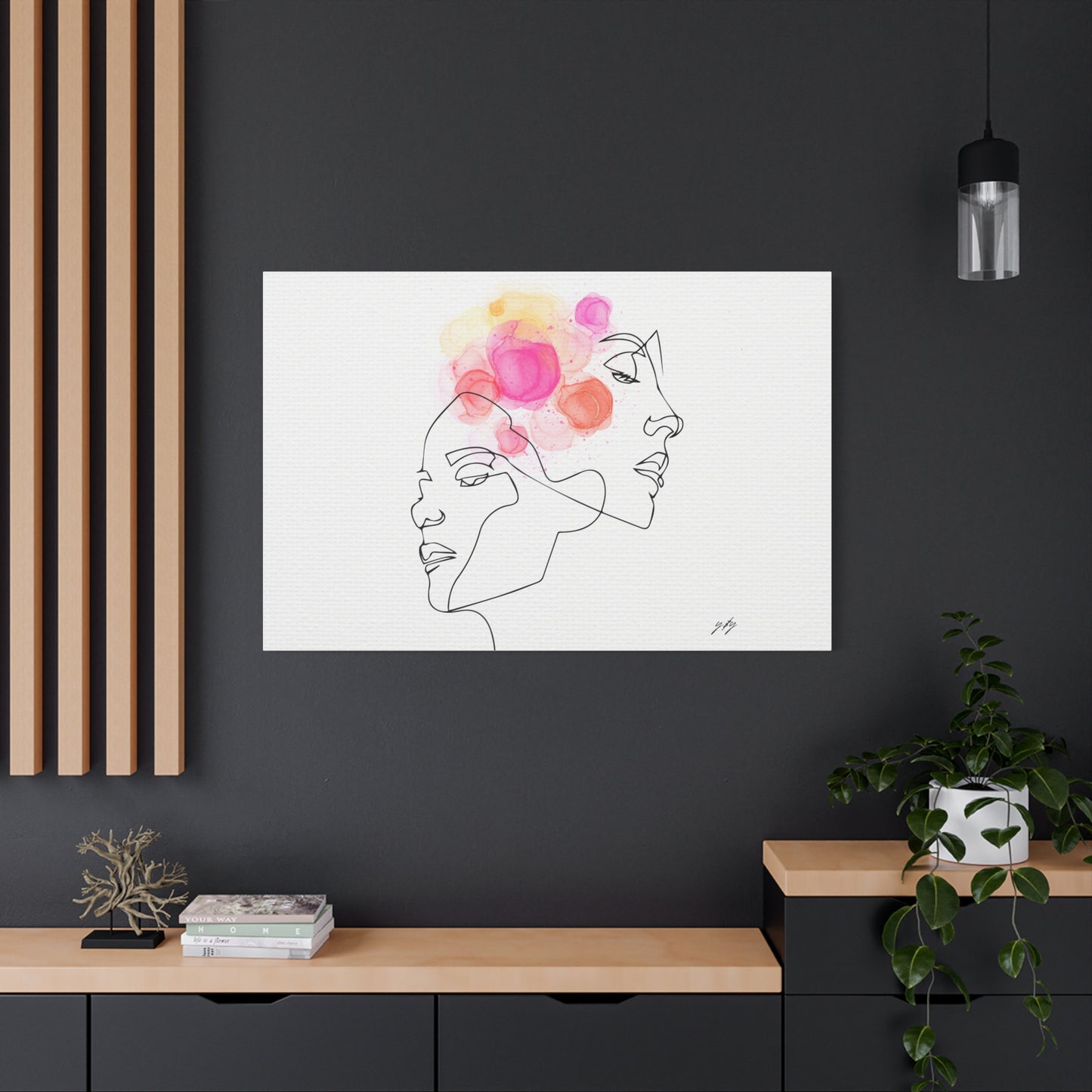 Framed artwork of a line drawing of a face with colorful flowers on a dark wall.